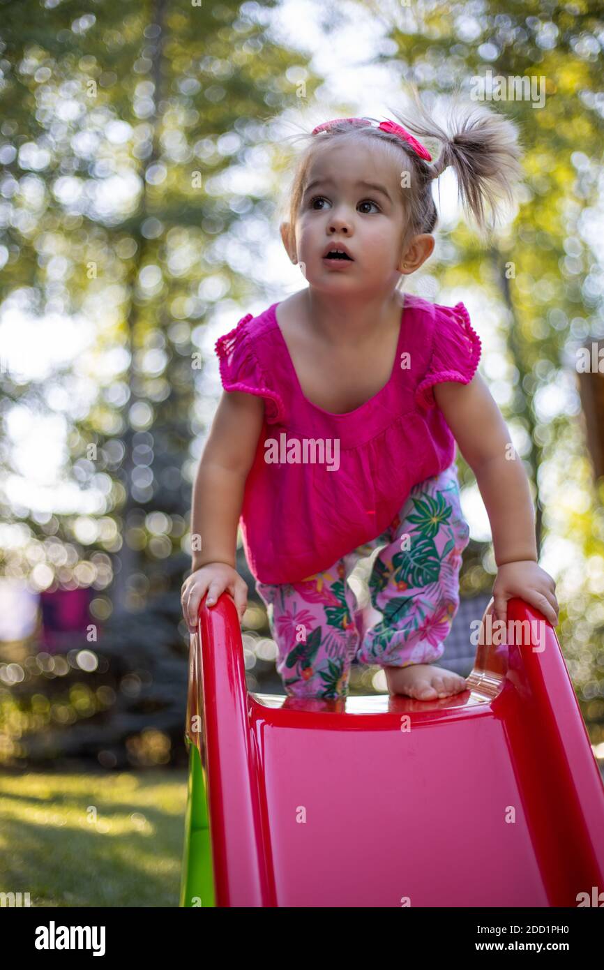 Petite fille sur une aire de jeux avec parc flou jardin flou arrière-plan. Joli portrait de fille sur la diapositive Banque D'Images