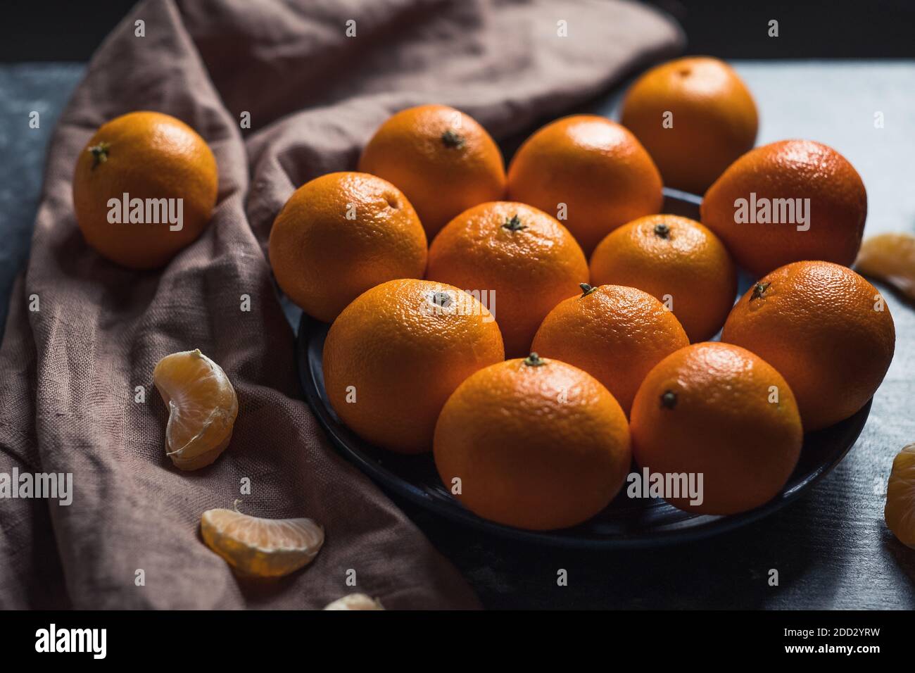 Pile de mandarine orange mûre ronde non pelée dans une assiette. Banque D'Images