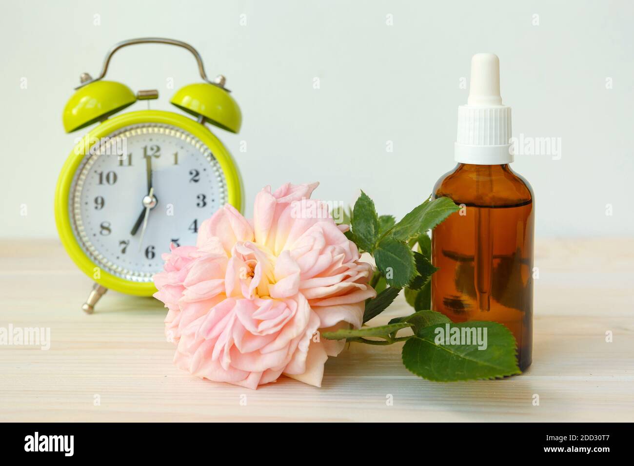 Rose et bouteille avec de l'huile aromatique ou des médicaments. Réveil de style rétro Banque D'Images