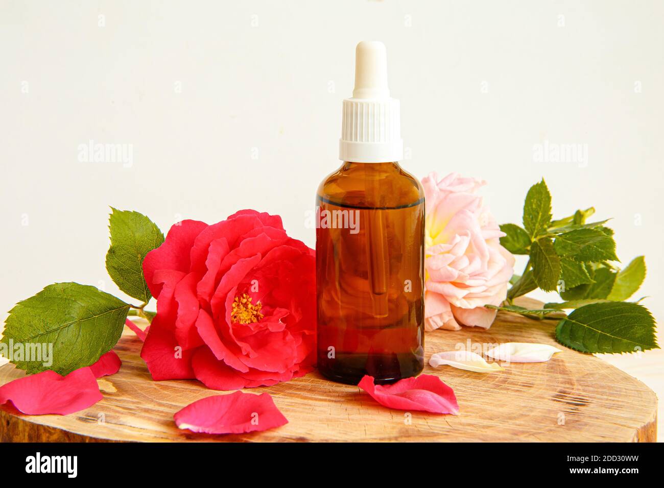 Rose et bouteille avec de l'huile aromatique ou un médicament sur un support en bois Banque D'Images