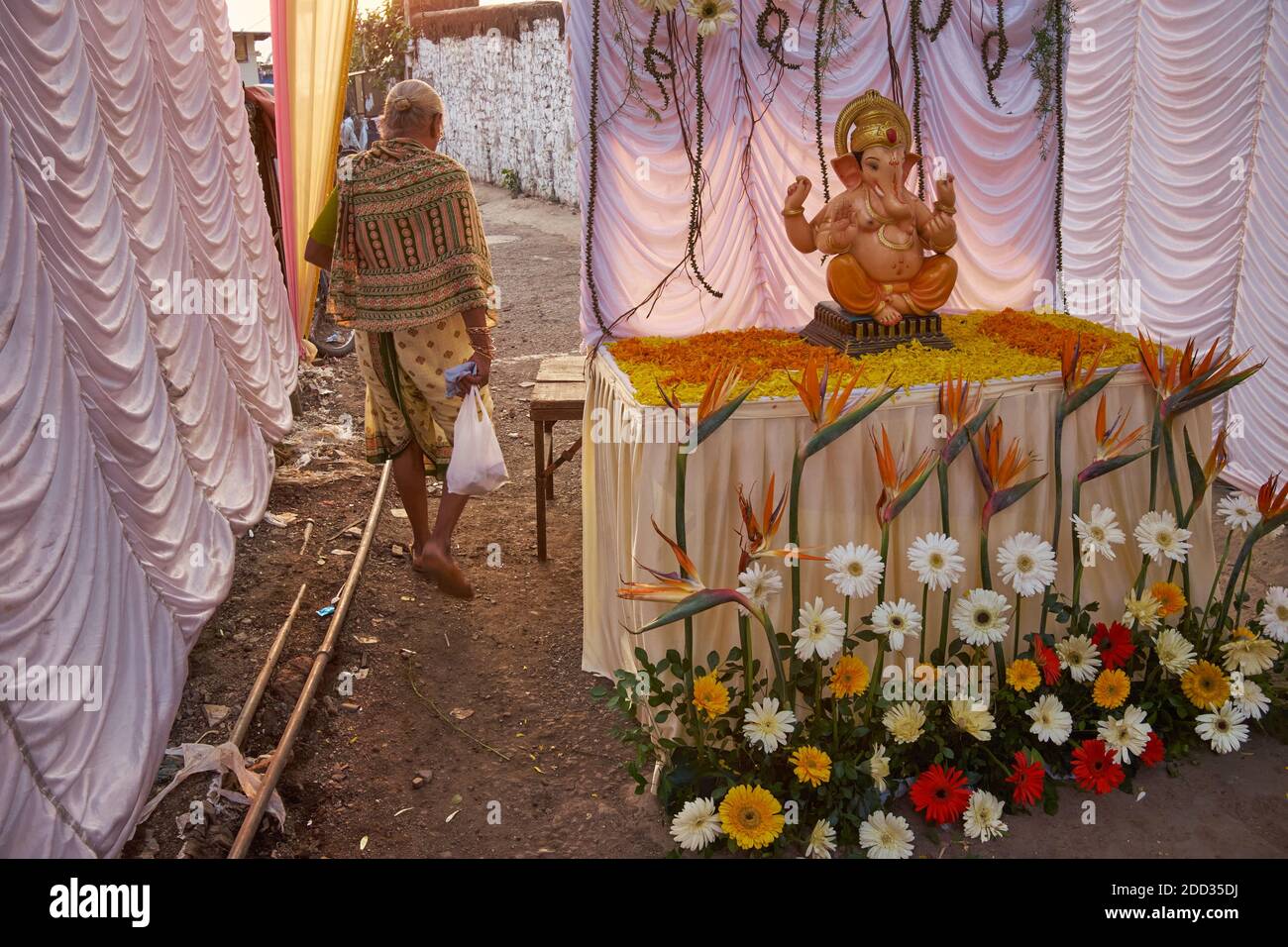 Une femme passe devant une figure de dieu éléphant hindou Ganesh (Ganesha, Ganpati) debout sans surveillance dans le cadre de la décoration du festival; Mumbai, Inde Banque D'Images