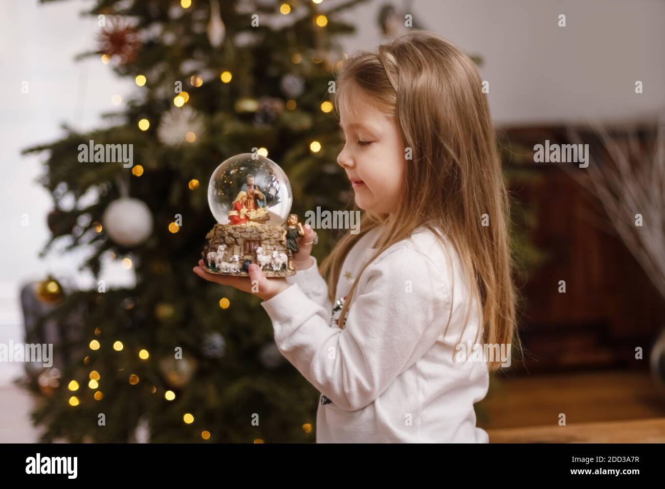 Fille regardant une boule de verre avec une scène de La naissance de Jésus-Christ dans une boule de verre Banque D'Images