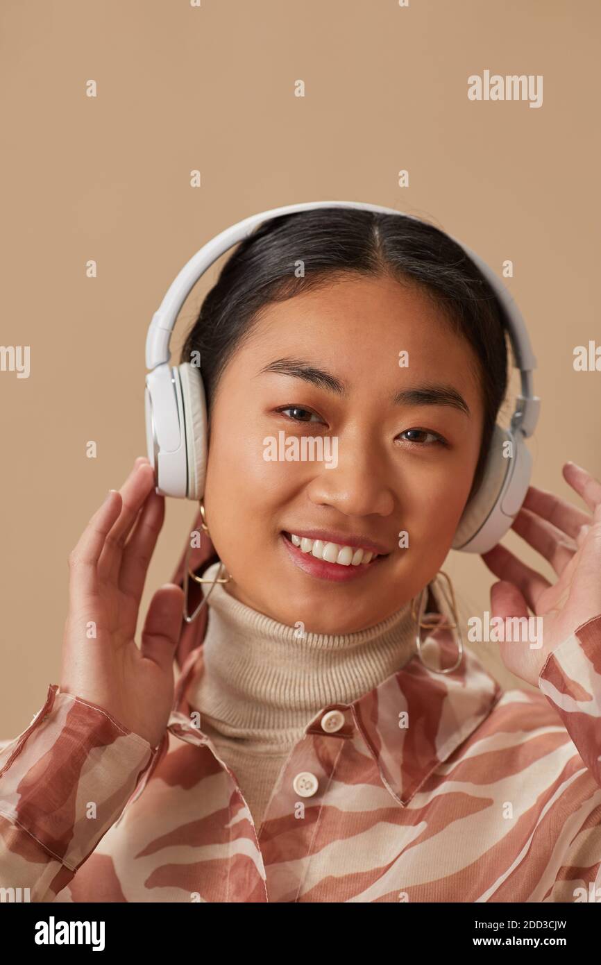 Portrait d'une jeune femme asiatique dans un casque sans fil à l'écoute musique et sourire à l'appareil photo Banque D'Images