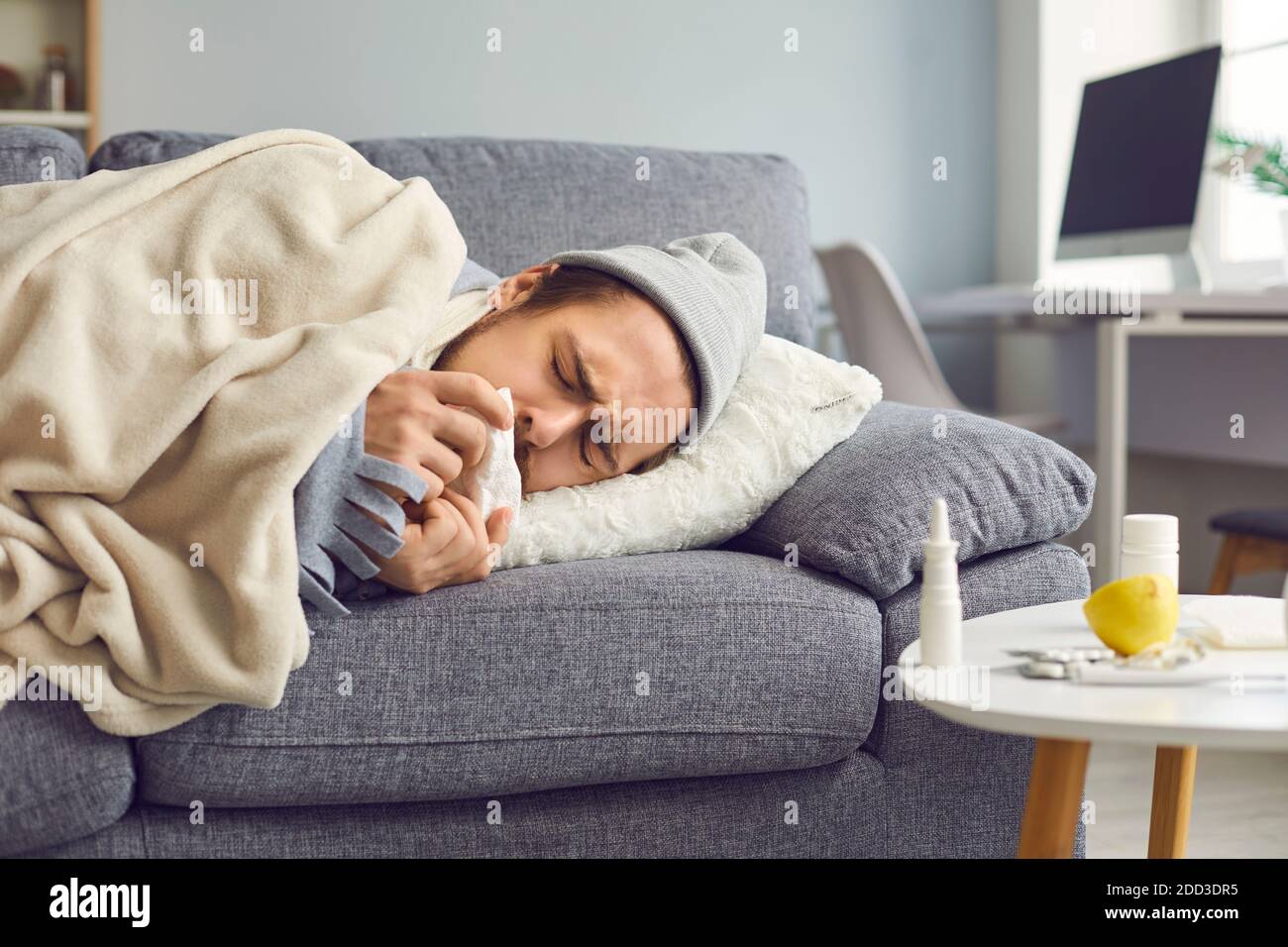 Gros plan d'un malade avec un nez qui coule et une serviette dans les mains couchée sur le canapé. Banque D'Images