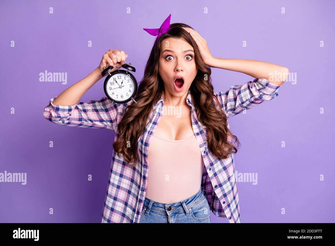 Photo d'une jeune femme tient la tête du réveil ouverte bouche tenue à  l'étoile chemise à carreaux style rétro bandeau couleur violet isolée  arrière-plan Photo Stock - Alamy