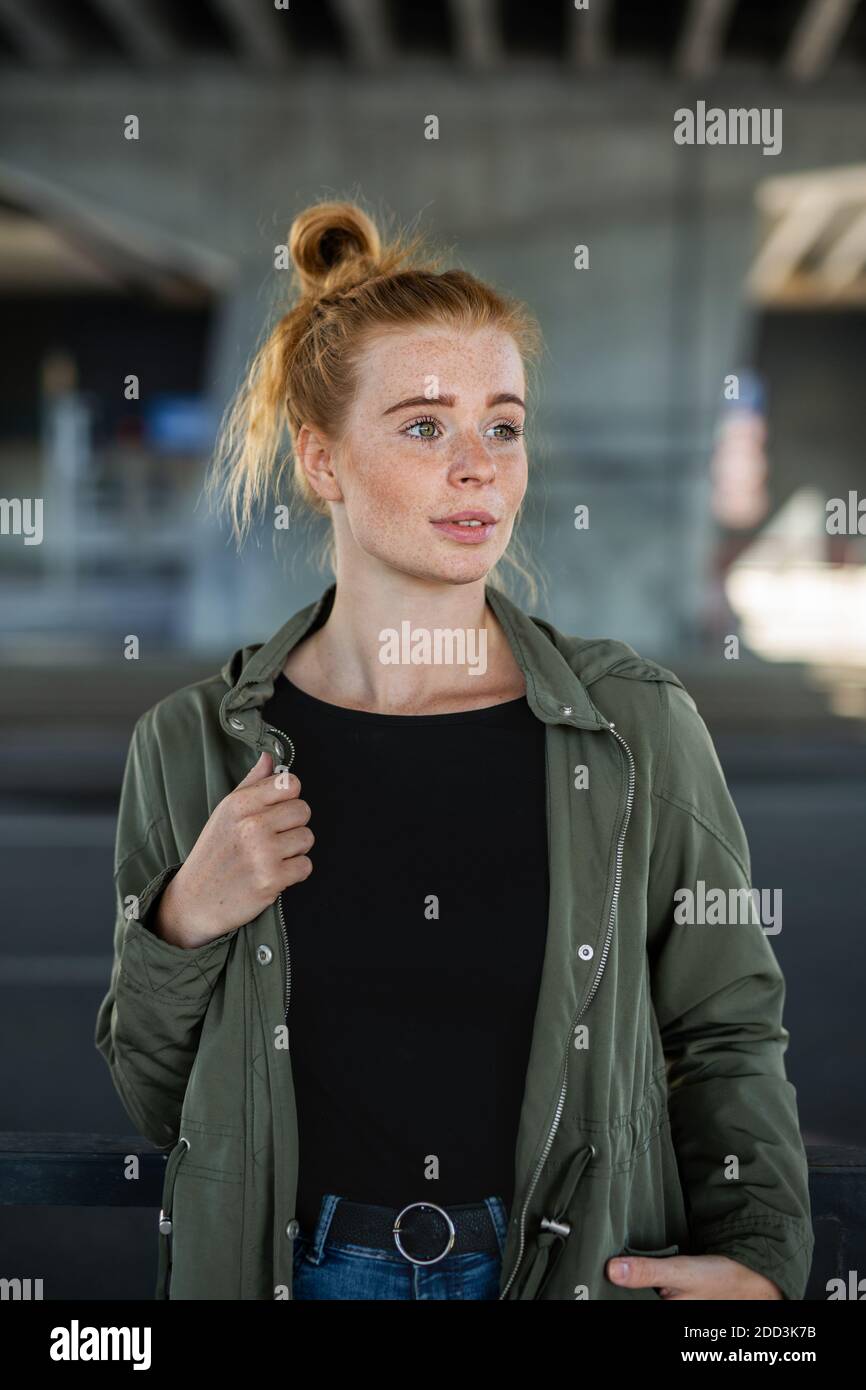 Portrait de jeune femme gaie avec des cheveux rouges dehors en ville, debout. Banque D'Images