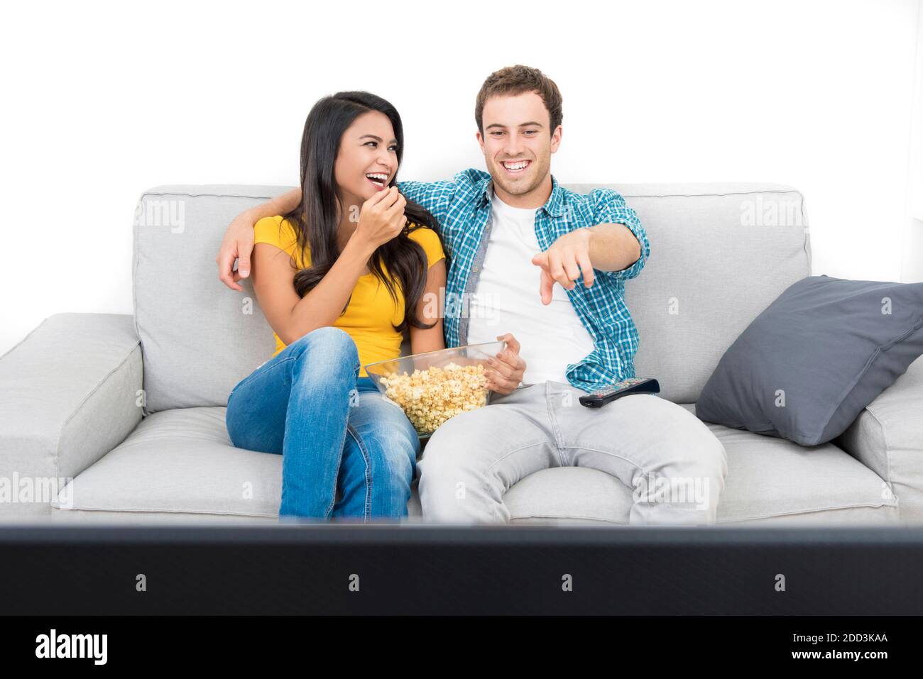 Jeune heureux couple interracial regardant la télévision sur le canapé dedans séjour Banque D'Images