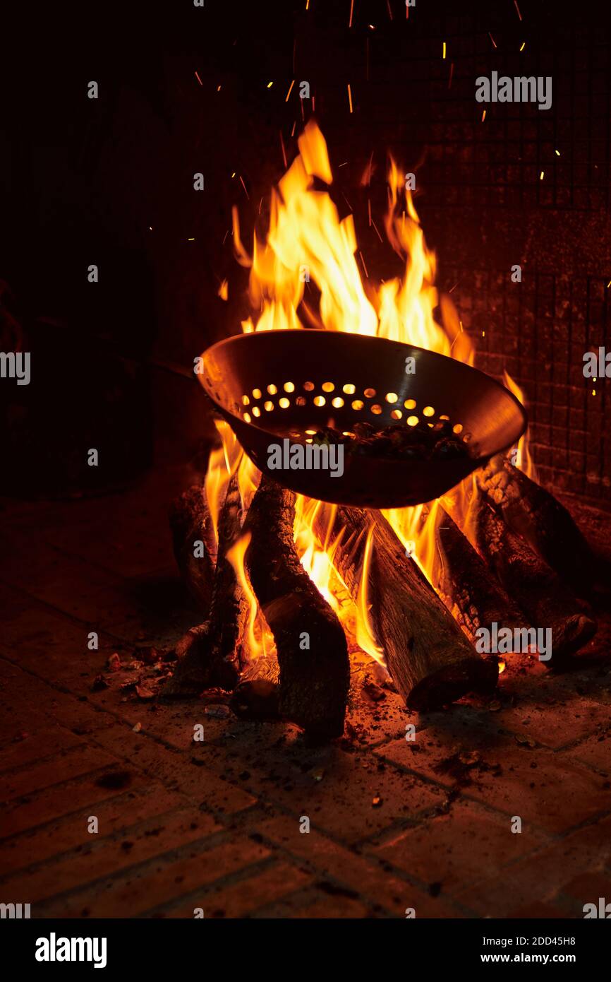 châtaignes rôtisant sur le feu dans une poêle typique au-dessus d'une cheminée. concept rural et tradition du village Banque D'Images