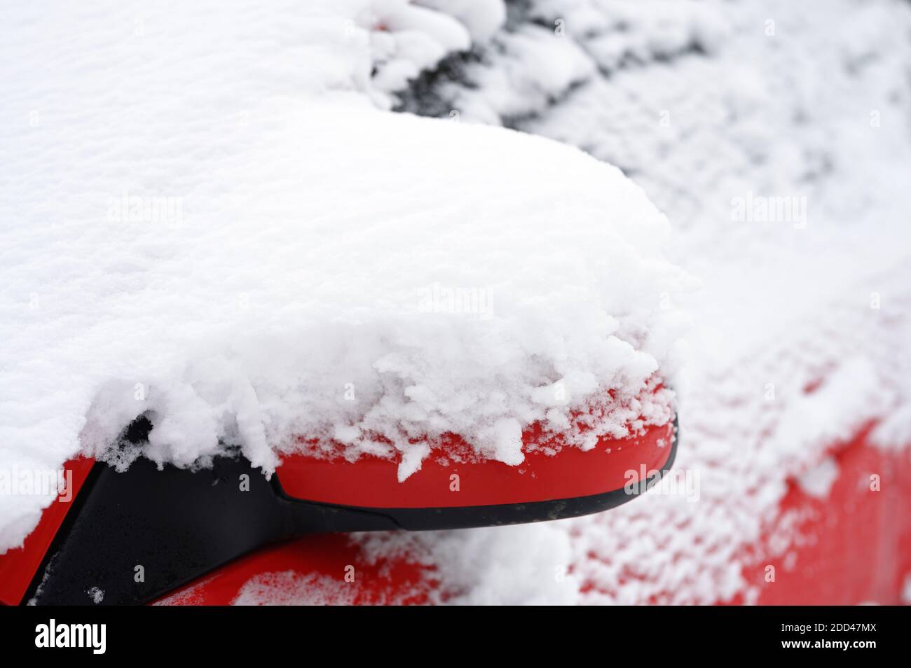 une voiture rouge couverte de neige est garée dans une ville rue pendant la saison hivernale enneigée Banque D'Images