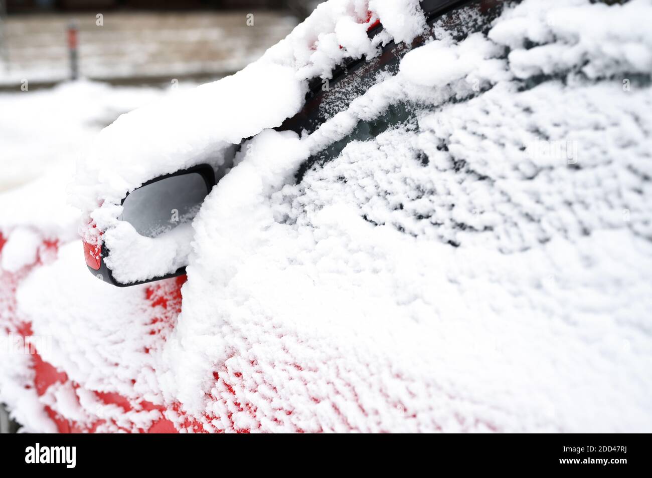 une voiture rouge couverte de neige est garée dans une ville rue pendant la saison hivernale enneigée Banque D'Images