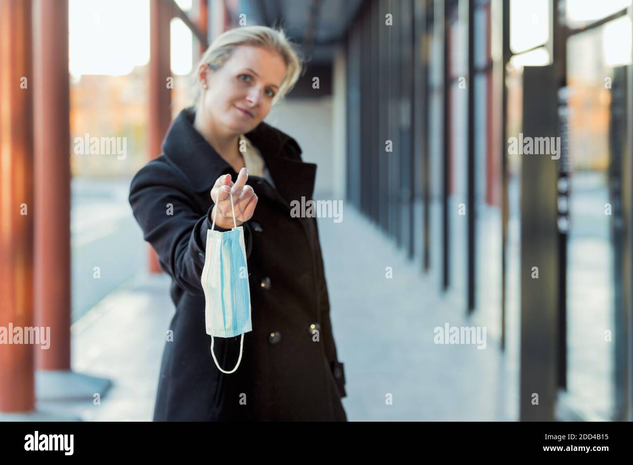 jeune femme blonde donnant son masque, drôle corona denier concept Banque D'Images