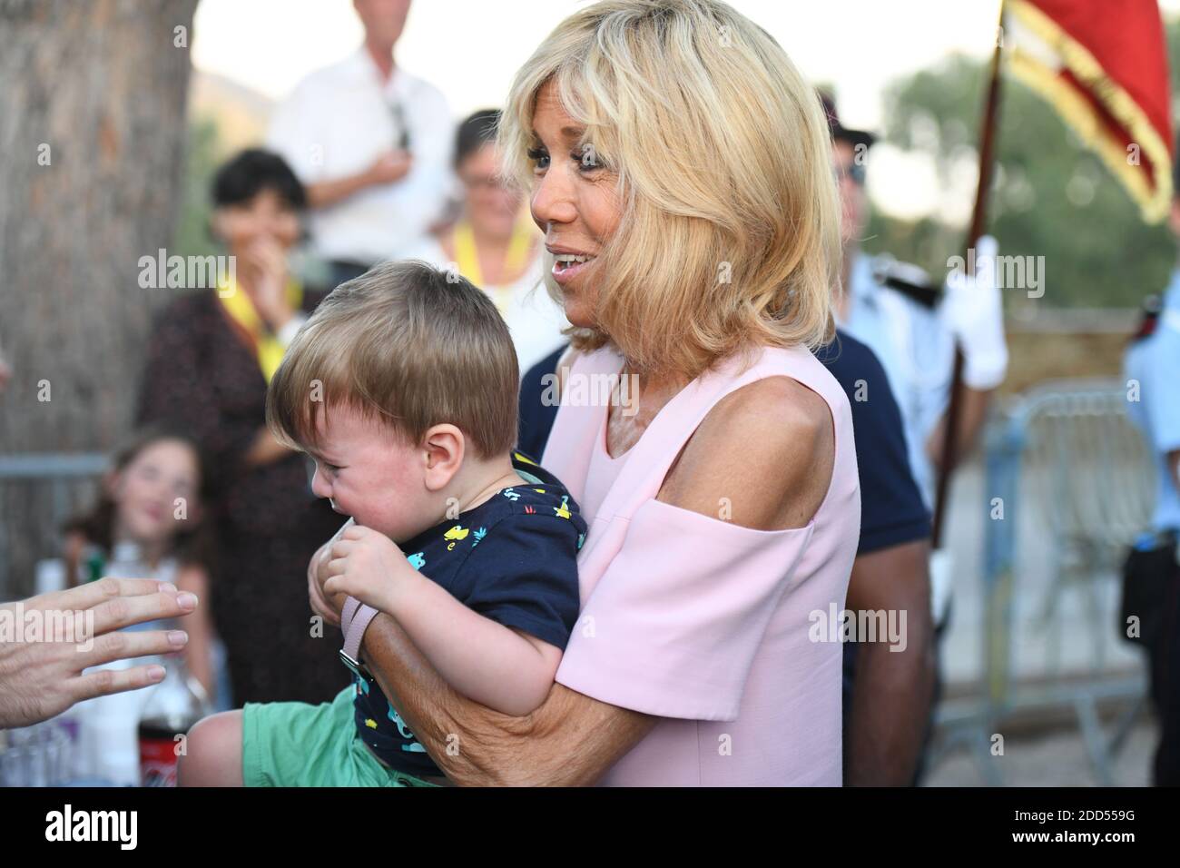Brigitte Macron porte un petit garçon après le 74e anniversaire de la  libération de Bormes-les-Mimosas pendant la Seconde Guerre mondiale, le 17  août 2018, à Bormes-les-Mimosas, dans le sud de la France.