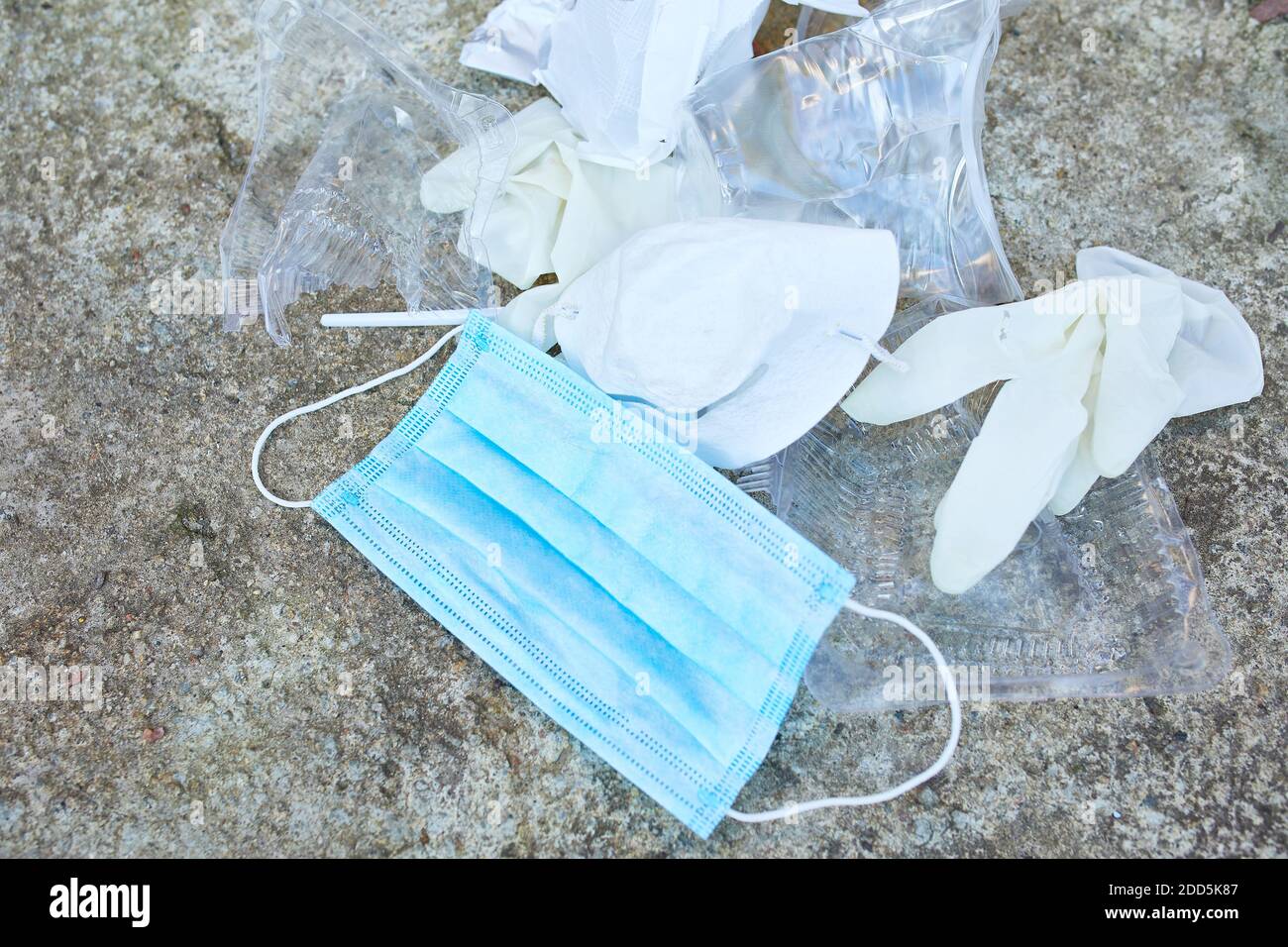 Un globe dans une pile de déchets éparpillés sur le fond de la route , autour de plastique dispersé, masque protecteur, gants, déchets pendant la pandémie du coronavirus. Enregistrer Banque D'Images