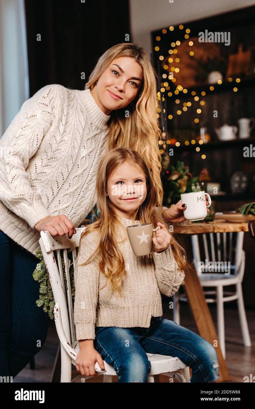 Bonne petite fille et sa mère mangeant des biscuits avec du lait à la maison. Joyeux Noël Banque D'Images