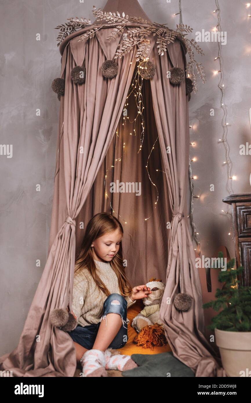 Bonne bourile petite fille est assise dans la tente sur le fond avec des lumières. Joyeux Noël Banque D'Images