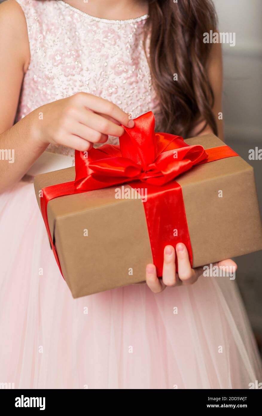 Une fille dans une robe chic se tient avec un cadeau du nouvel an dans ses  mains contre le fond d'un arbre du nouvel an Photo Stock - Alamy
