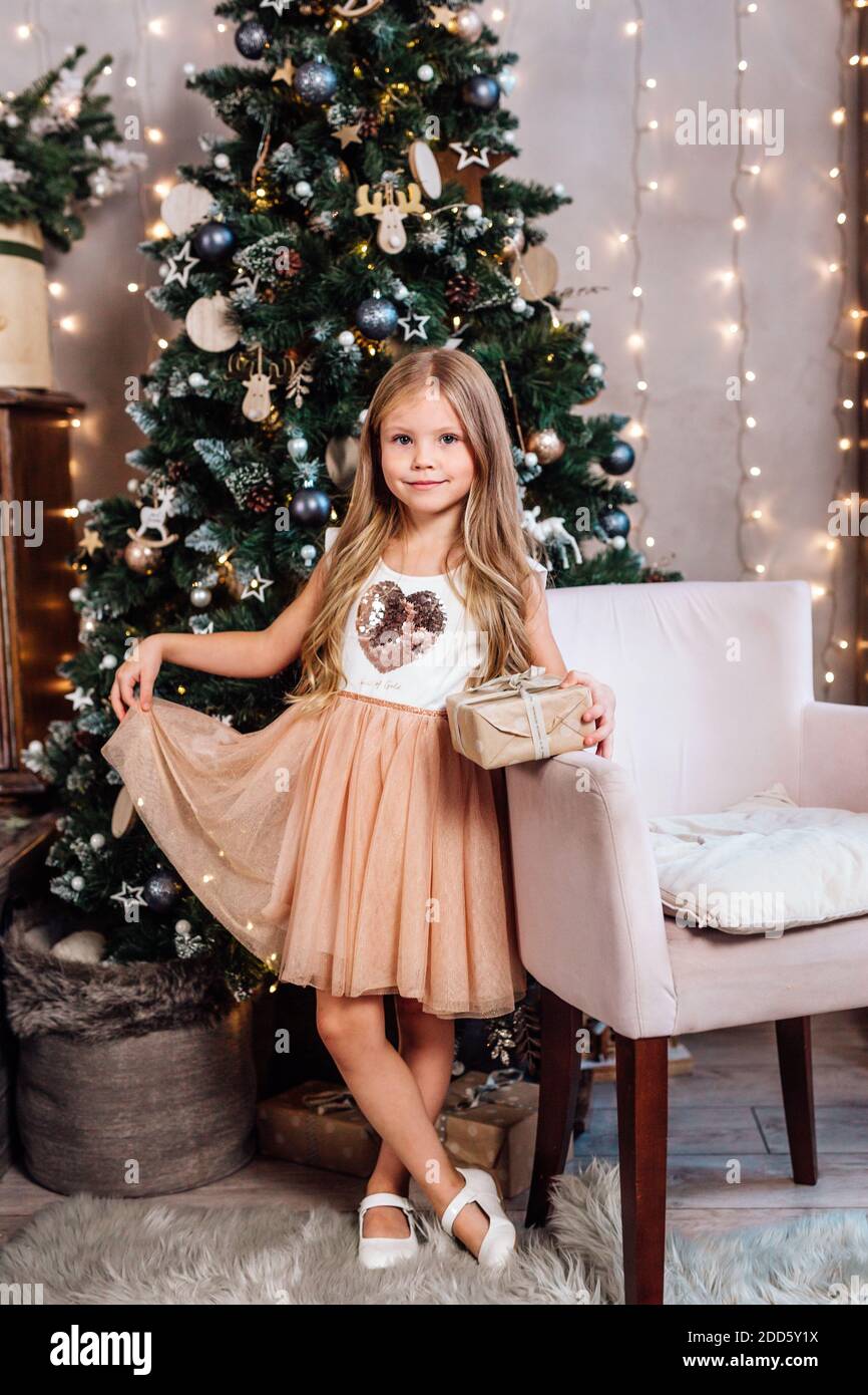 Belle petite fille en robe avec cadeau près de l'arbre de Noël à la maison Banque D'Images