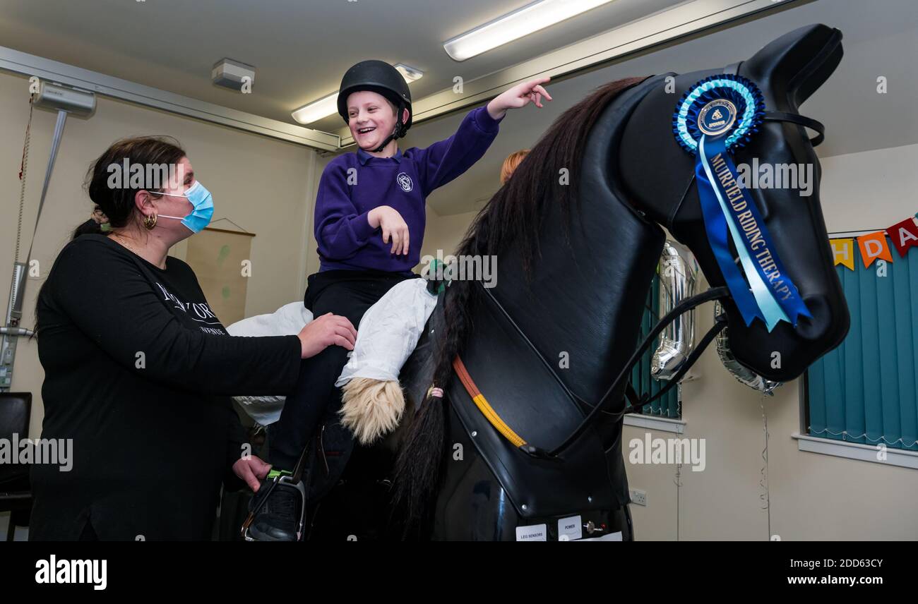 East Lothian, Écosse, Royaume-Uni, NHS Lothian & Muirfield Riding Therapy célèbre 10 ans d'hippothérapie : la physiothérapeute Heather Falconer a été la première à proposer le Children's Therapeutic Riding Service (service d'équitation thérapeutique pour les enfants) en offrant gratuitement de l'équitation thérapeutique aux enfants, aux jeunes et aux adultes handicapés. Le service a été le premier en Écosse pour les enfants ayant des problèmes de mobilité, d'équilibre, de tonus musculaire et de coordination. Oreo, un cheval mécanique, permet aux jeunes d'avoir de la physiothérapie amusante. Kyle Clark, âgé de 8 ans, fait le tour du simulateur de cheval mécanique de Racewood Banque D'Images