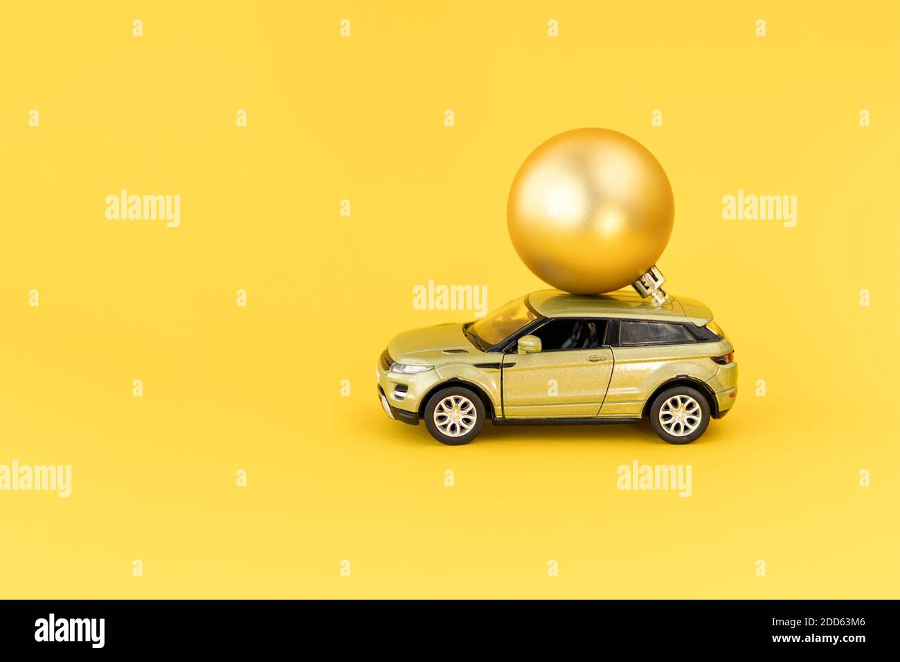 Modèle de voiture jaune avec boule de Noël dorée sur fond jaune. Concept à venir Noël ou Noël et nouvel an. Noël arrive. Copier l'espace Banque D'Images