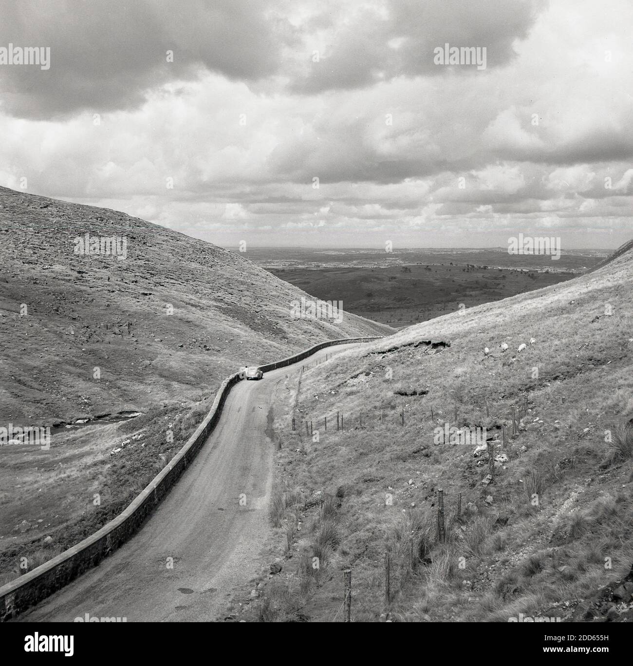 Années 1950, photo historique de j Allan Cash, une voiture de l'époque garée sur une route de campagne vide sur la spectaculaire route côtière de la chaussée d'Antrim, Irlande du Nord, Royaume-Uni. Banque D'Images