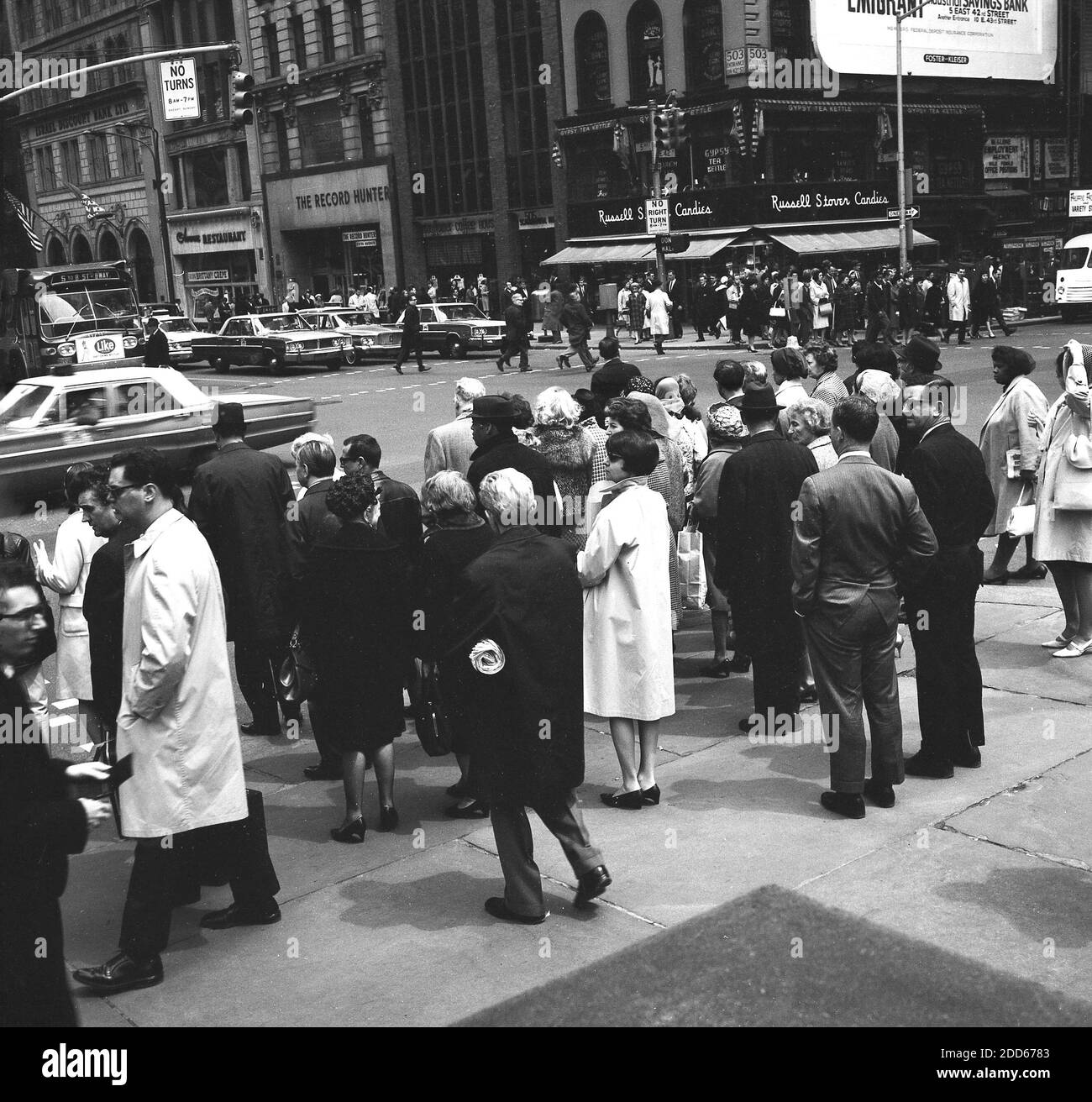 Années 1960, historique, Manhattan, à l'angle de la 5e Avenue, New Yorkers attendant de traverser la 42e rue, une grande rue transversale dans le quartier de New City de Manhattan. La rue est célèbre pour son théâtre et sa vie nocturne et abrite certains des bâtiments et monuments les plus connus de la ville. Banque D'Images