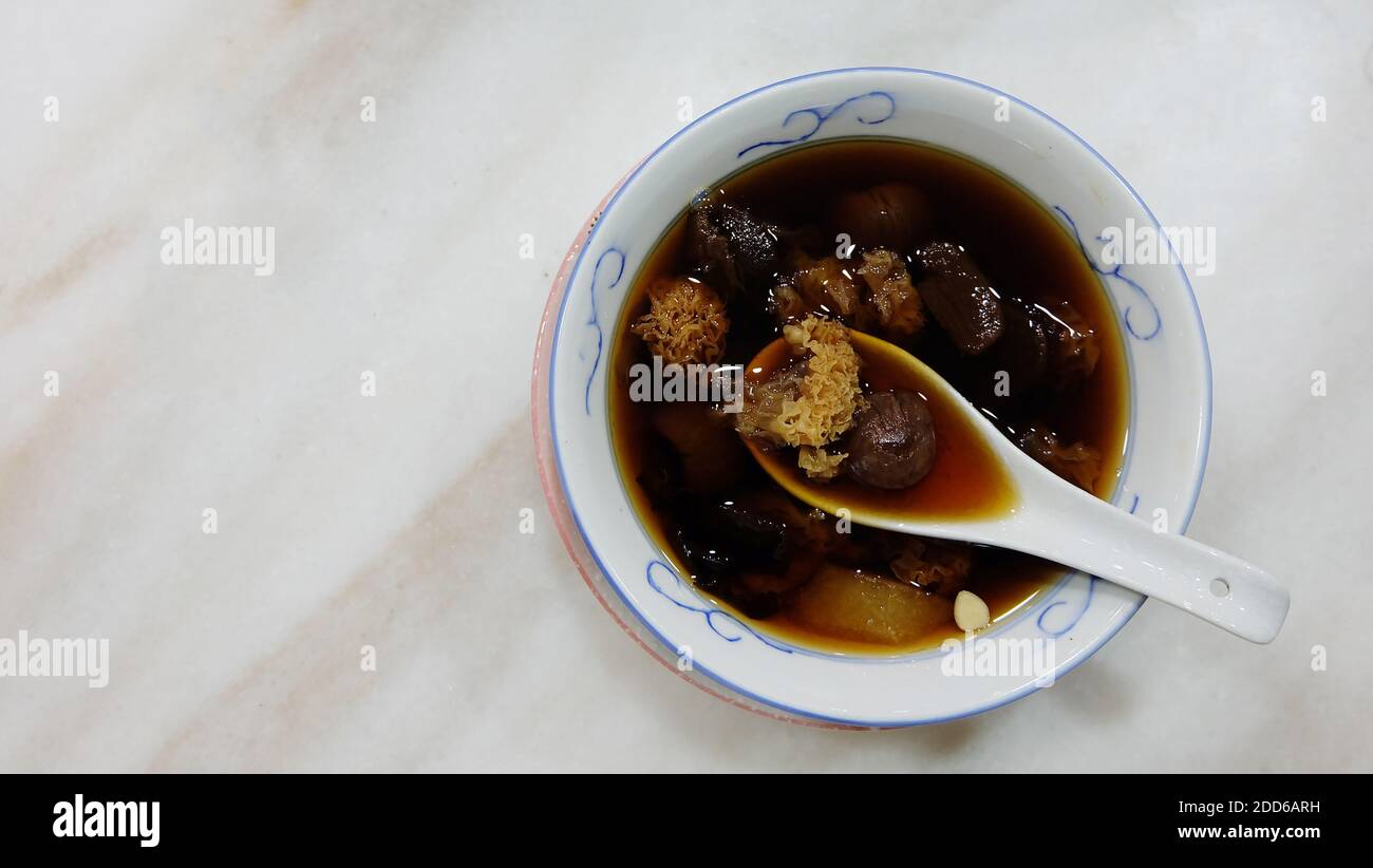 Soupe de champignons blancs chinois et de palangane, dans un bol avec une cuillère à soupe chinoise, placé sur une table en marbre. Vue de dessus. Banque D'Images