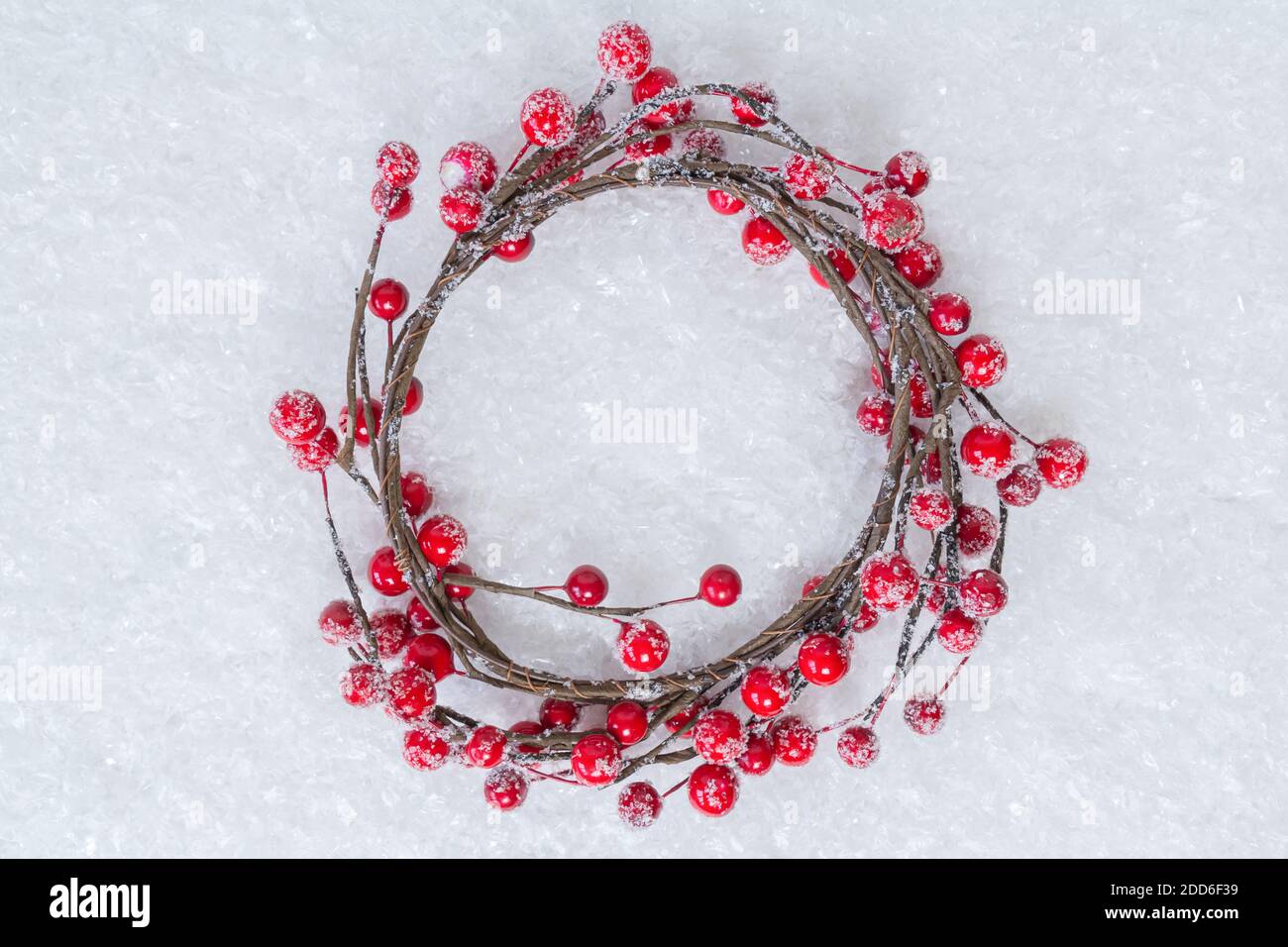 Couronne de Noël de brindilles avec baies de houx rouges sur fond de neige blanche. Couronne de fruits rouges des fêtes. Thème des vacances d'hiver. Bonne Année. Copier l'espace pour Banque D'Images