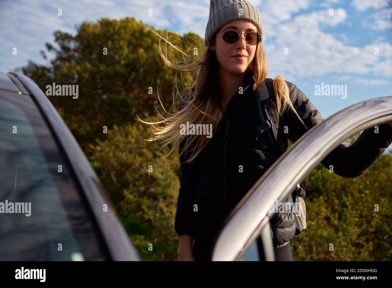 Jeune femme portant des lunettes de soleil et bonnet beanie avec sac à dos  obtenir voiture de location avant de partir en randonnée Photo Stock - Alamy