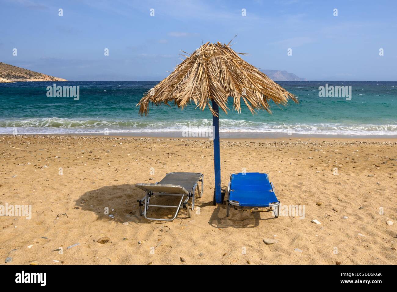 Chaises longues et parasol à la plage d'Agia Theodoti sur l'île d'iOS. Une plage merveilleuse avec le sable doré et les eaux azur. Cyclades, Grèce Banque D'Images