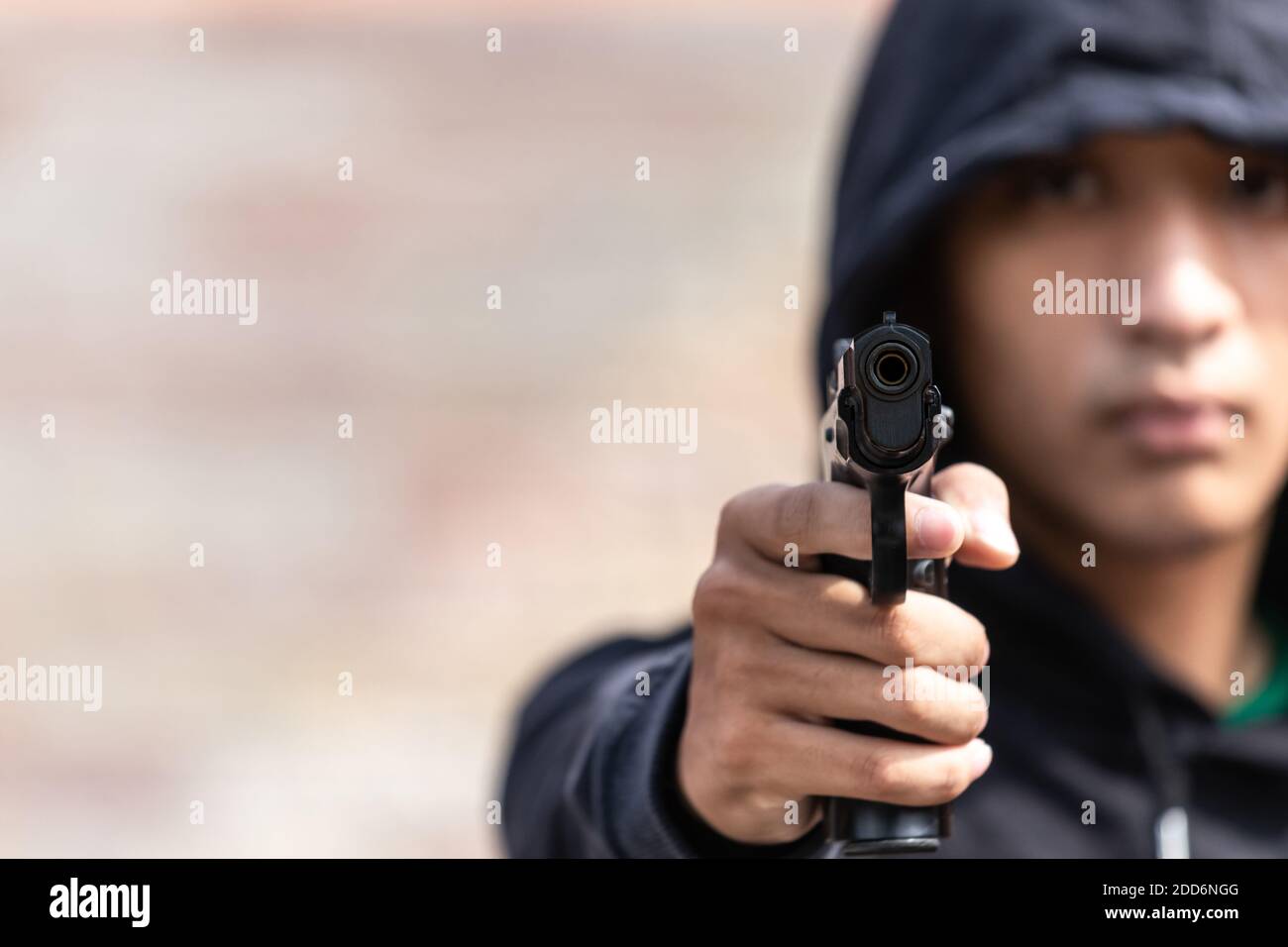 Le gangster a dirigé un pistolet vers la caméra. Un voleur pointant un fusil vers la cible, focus sélectif sur le canon avant, focus flou. Banque D'Images