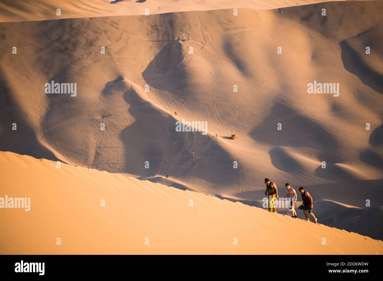 Des personnes grimpant des dunes de sable pour observer le coucher de soleil sur le désert à Huacachina, région de l'ICA, Pérou, Amérique du Sud Banque D'Images