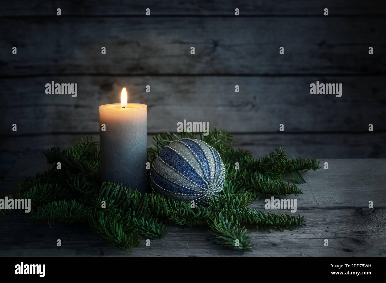 Bougie en feu et boule de Noël bleue sur branches de sapin sur fond gris foncé de planches rustiques en bois, espace de copie, foyers doux sélectionnés Banque D'Images