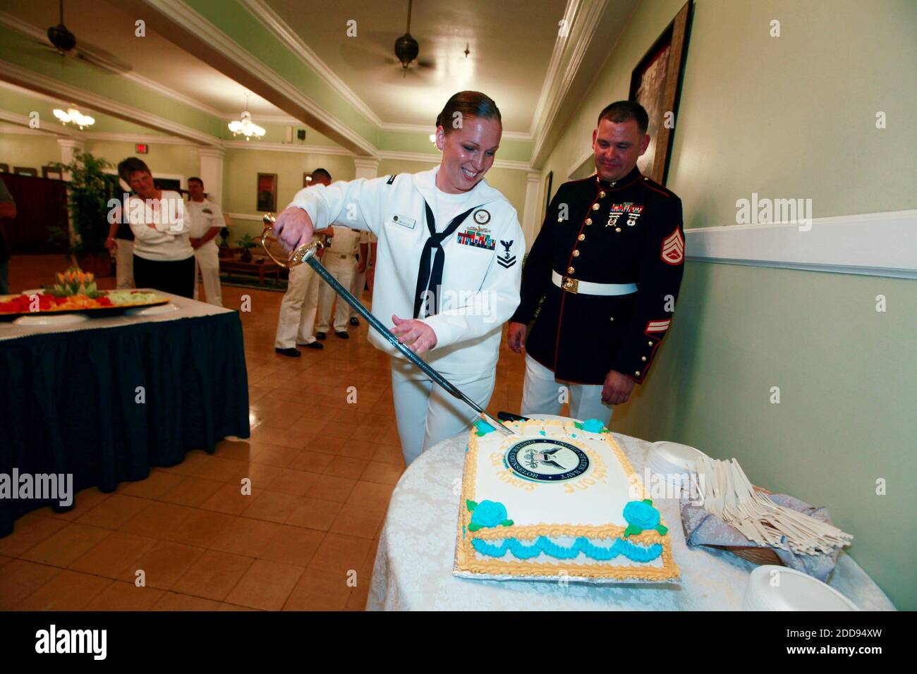 PAS DE FILM, PAS DE VIDÉO, PAS de TV, PAS DE DOCUMENTAIRE - l'officier de la marine de 2e classe Desiree Rivers utilise le sabre de son mari du corps des Marines pour couper son gâteau de réenrôlement au Bayview Club de la base de la marine américaine à Guantanamo Bay, Cuba, le 27 mars 2009. Son mari, Sgt. David Rivers, à droite, portait sa robe de blues pour l'occasion. Photo de John VanBeekum/Miami Herald/MCT/ABACAPRESS.COM Banque D'Images