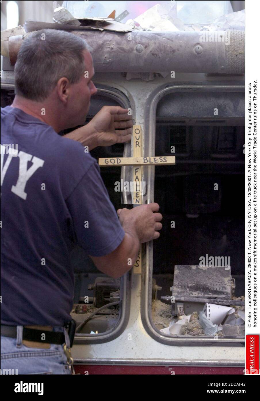 PAS DE FILM, PAS DE VIDÉO, PAS DE TV, PAS DE DOCUMENTAIRE - © PETER TOBIA/KRT/ABACA. 28608-1. New York-NY-USA. 13/09/2001. Un pompier de la ville de New York place une croix en hommage à ses collègues sur un monument commémoratif de fortune installé jeudi sur un camion de pompiers près des ruines du World Trade Center. Banque D'Images PAS DE FILM, PAS DE VIDÉO, PAS DE TV, PAS DE DOCUMENTAIRE - © PETER TOBIA/KRT/ABACA. 28608-1. New York-NY-USA. 13/09/2001. Un pompier de la ville de New York place une croix en hommage à ses collègues sur un monument commémoratif de fortune installé jeudi sur un camion de pompiers près des ruines du World Trade Center. Banque D'Images