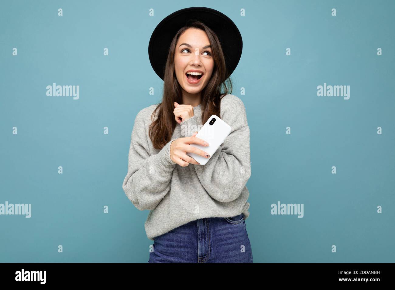 Image d'une jeune femme heureuse et belle posant isolée arrière-plan mural bleu à l'aide d'un téléphone portable Banque D'Images