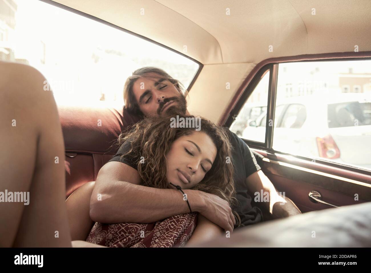 Jeune couple dormant en voiture par beau temps Banque D'Images