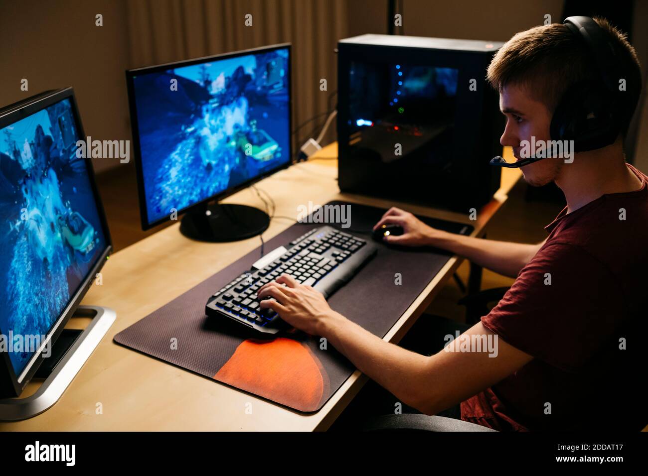 Jeune homme jouant à des jeux vidéo avec un ordinateur au bureau Banque D'Images