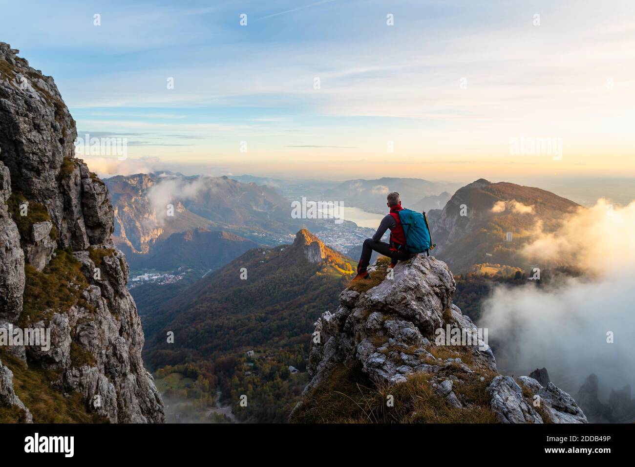 Randonneur pensif regardant la vue tout en étant assis sur le sommet de la montagne pendant le lever du soleil à Bergamasque Alpes, Italie Banque D'Images