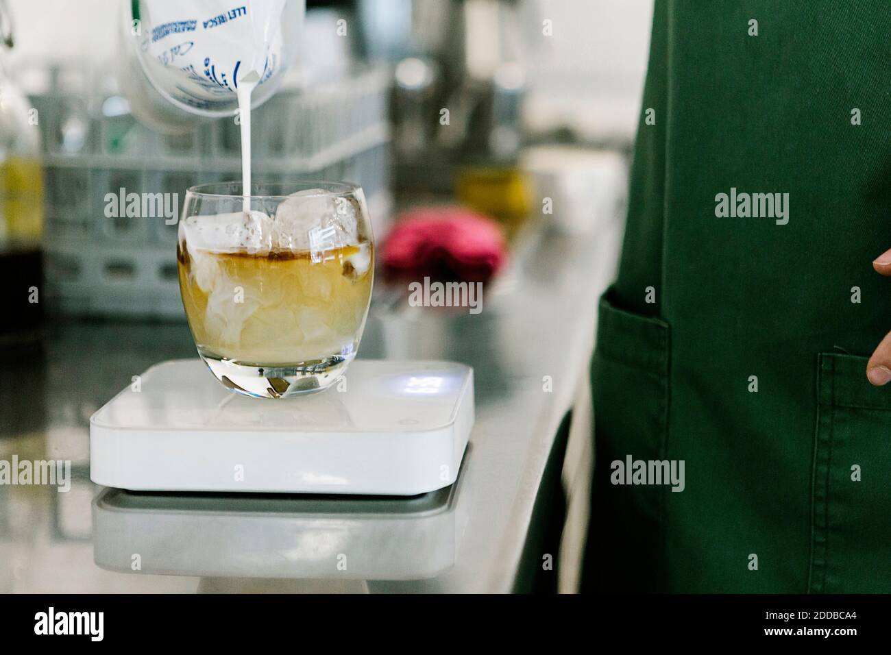 Le barista reste debout tout en versant du lait dans une tasse de café balance de cuisine au café-restaurant Banque D'Images