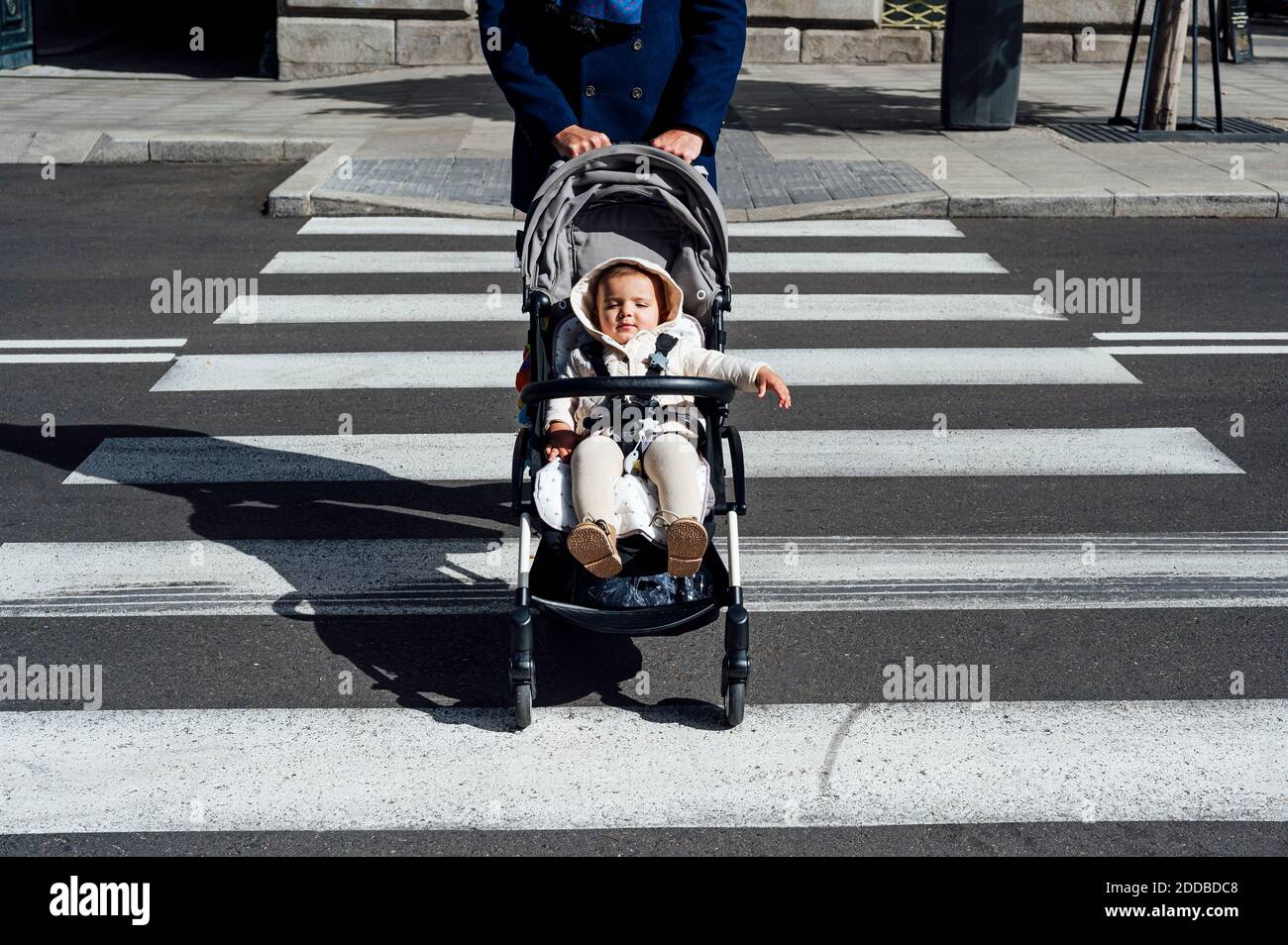Père avec bébé en poussette de bébé traversant la route en ville Banque D'Images