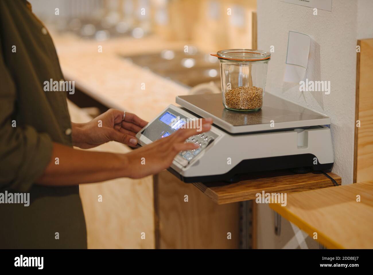 Section médiane de l'entrepreneur féminin pesant le pot de grain sur la balance dans le café Banque D'Images