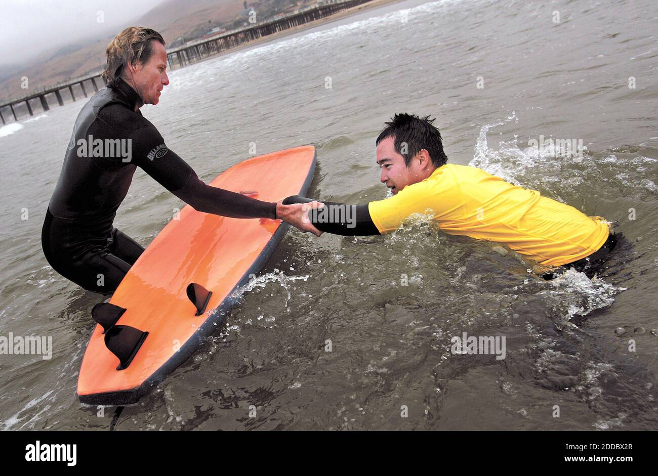 PAS DE FILM, PAS DE VIDÉO, PAS de TV, PAS DE DOCUMENTAIRE - Charlie Doty, à gauche, de Grover Beach, aide le Sgt de l'Armée à la retraite. Chang Wong de retour à son conseil d'administration après une wipeout à Pismo Beach, CA, États-Unis, le 16 août 2006. Wong a servi en Irak et a perdu les deux jambes sous le genou. Photo de Joe Johnston/San Luis Obispo Tribune/MCT/ABACAPRESS.COM Banque D'Images
