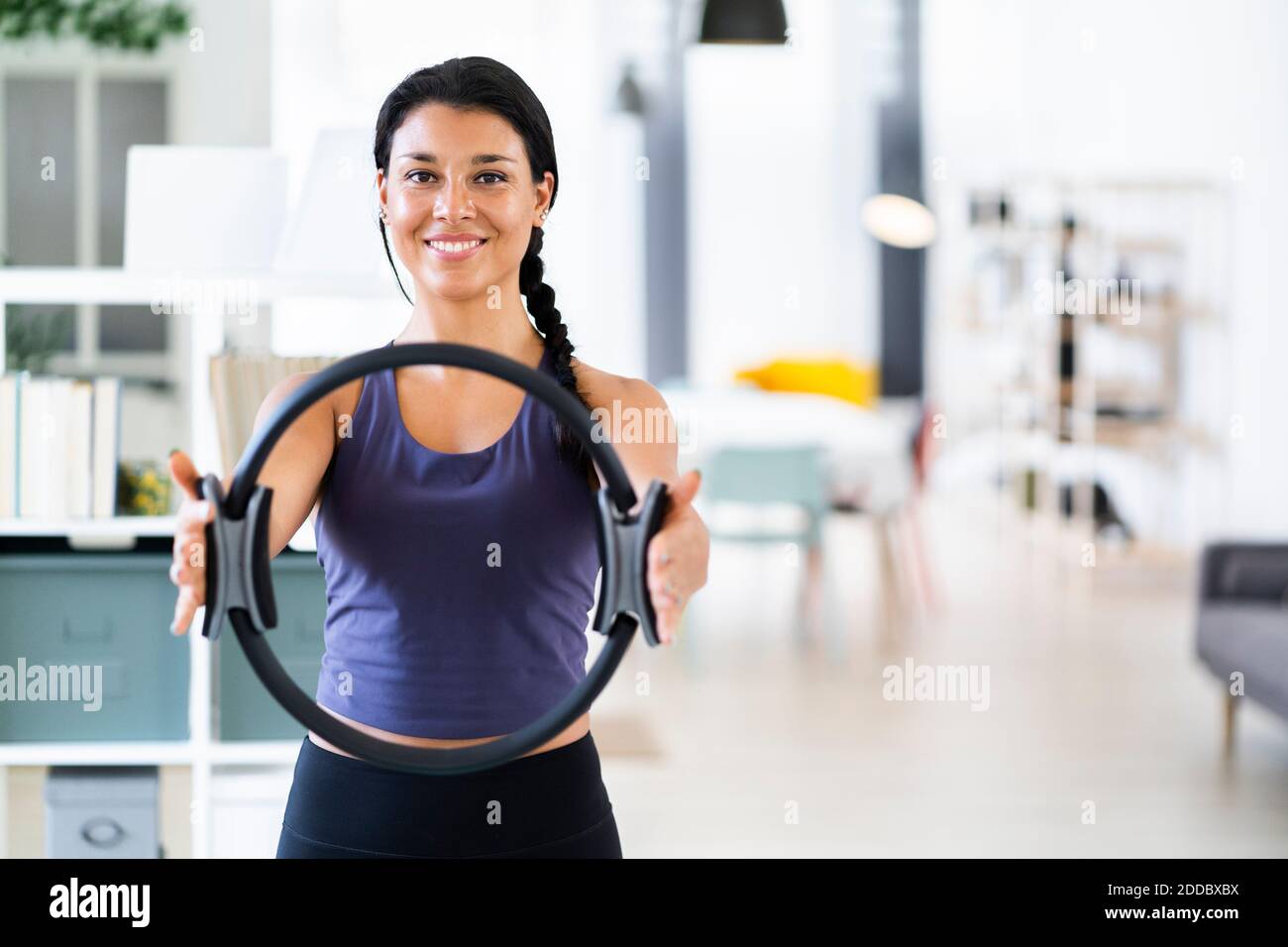 Souriante jeune femme faisant pilates anneau exercice tout en se tenant à accueil Banque D'Images