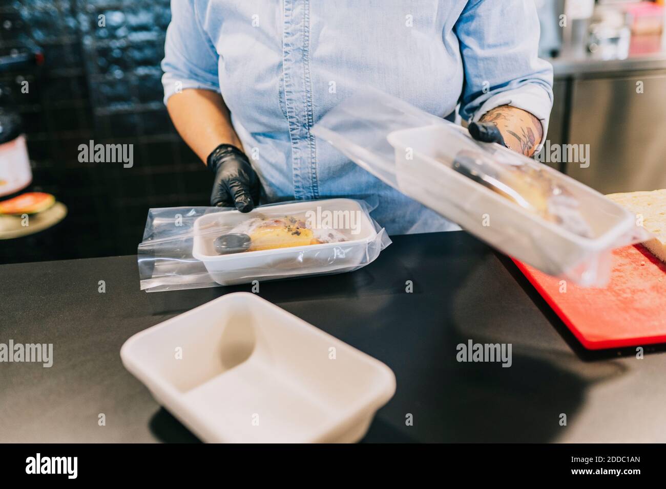 Section médiane du chef féminin proposant des repas à emporter au restaurant Banque D'Images