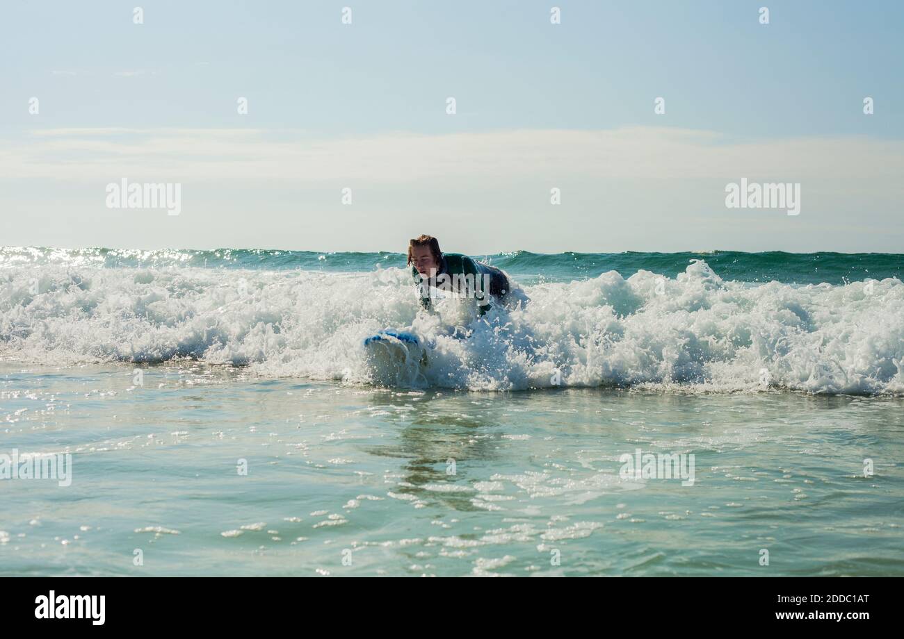 Un adolescent surfant sur la mer contre le ciel à la plage Banque D'Images