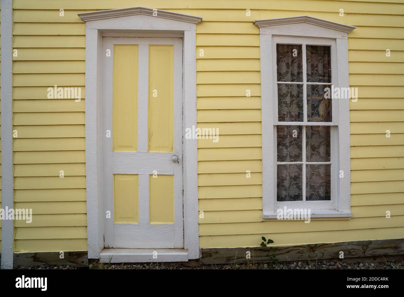 Extérieur d'une maison peinte en jaune, porte et fenêtre avec garniture blanche. Prise dans South Park Colorado, une ville fantôme Banque D'Images
