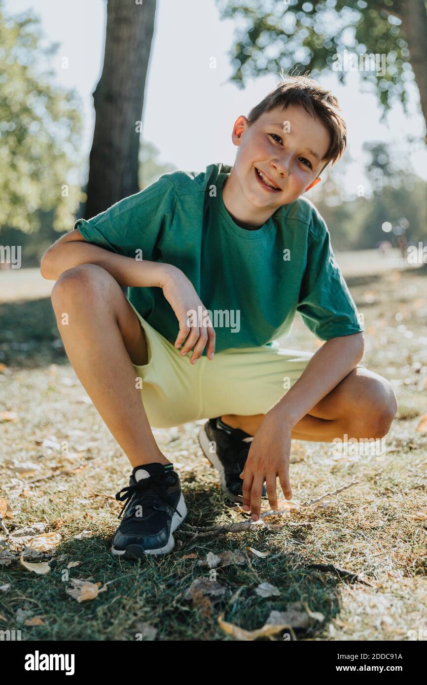 Un jeune garçon se caroupe dans un parc pubien exposé par beau temps