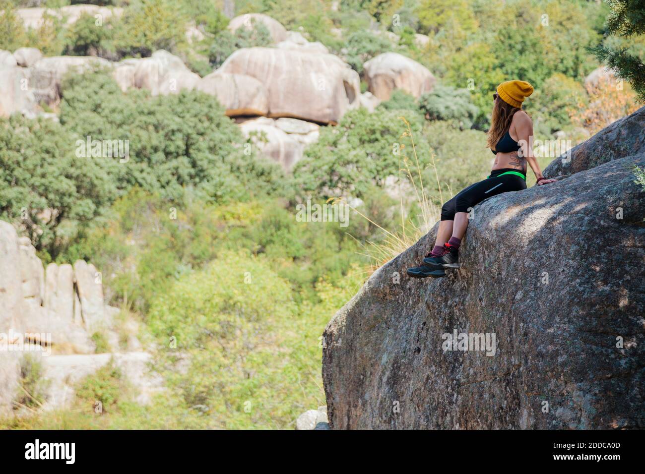 Trekker regardant la vue tout en se reposant sur le rocher dans la forêt à la Pedriza, Madrid, Espagne Banque D'Images