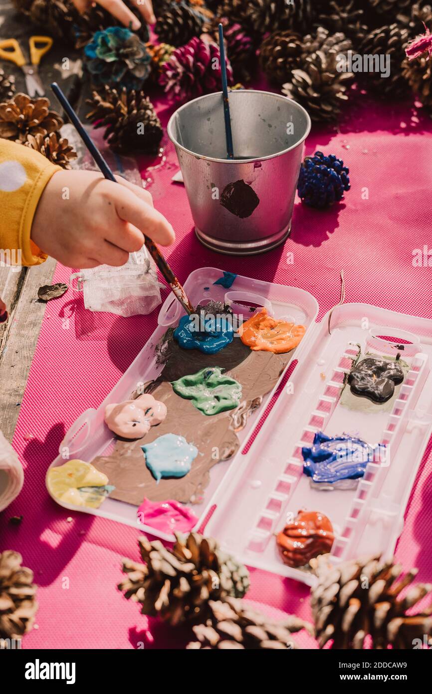 Main de fille mélangeant aquarelle sur la palette avec pinceau à table de pique-nique dans le parc pendant la journée ensoleillée Banque D'Images