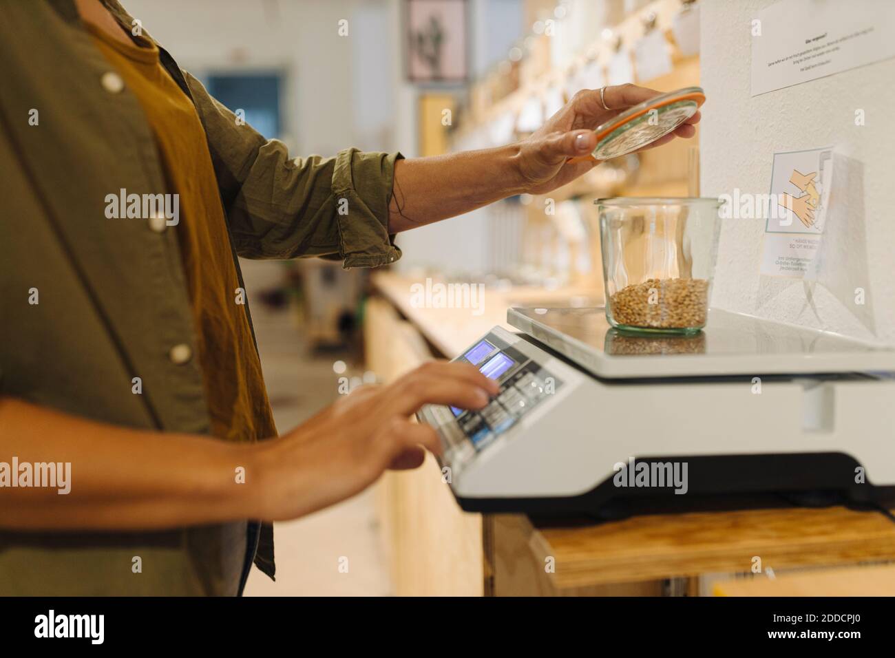 Section médiane de femme d'affaires pesant le pot de grain sur la balance à l'intérieur café Banque D'Images